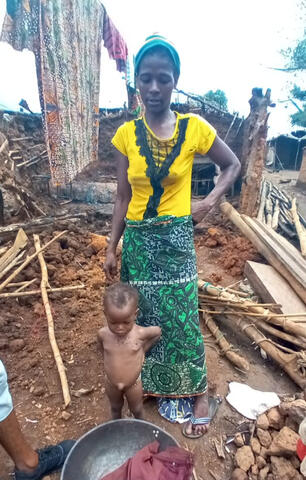 A mother and child stand in front of their burned home