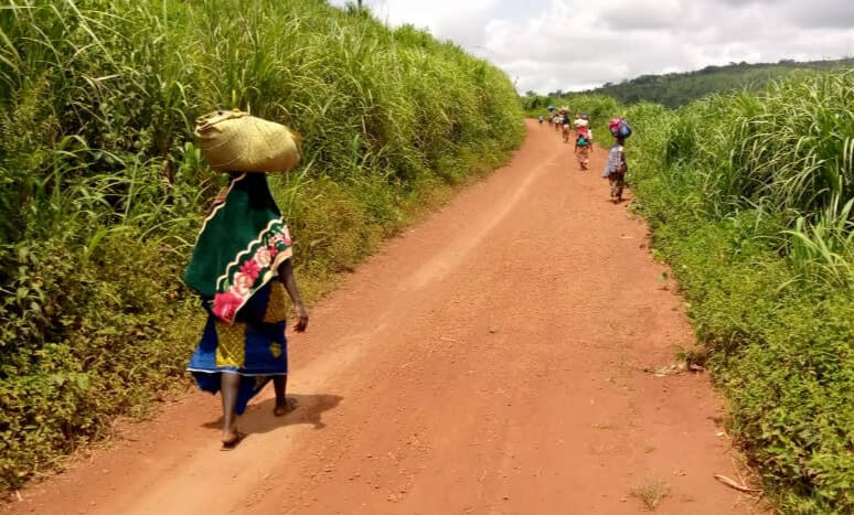 People carry their belongings as they walk from the village