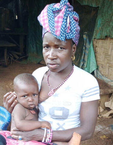 A mother and child sit outside looking uncertainly at the camera