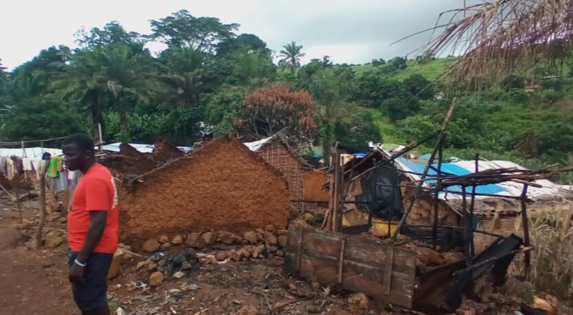 Villagers wander among the charred wreckage of the village